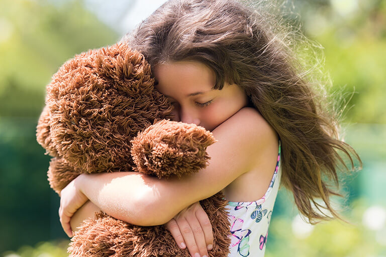 girl hugging a teddy bear